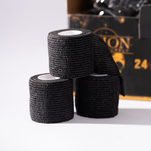 Three rolls of black tape stacked on a white surface with a branded box in the background.