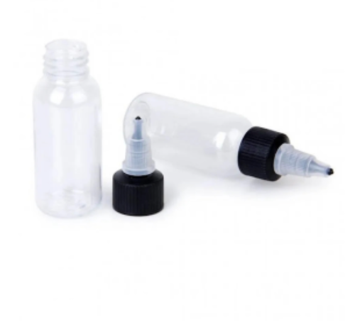 Two empty clear ink bottles with black caps and a spout, lying next to each other on a white background.